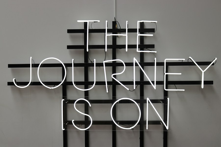 A neon sign that says the journey is on.