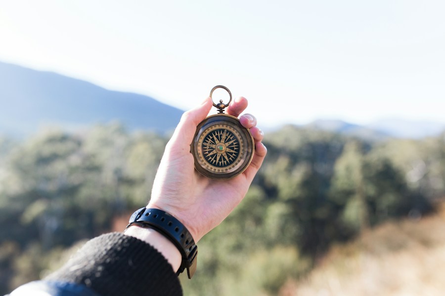 A person holding a compass, exploring the possibilities of free lancing with mountains in the background.