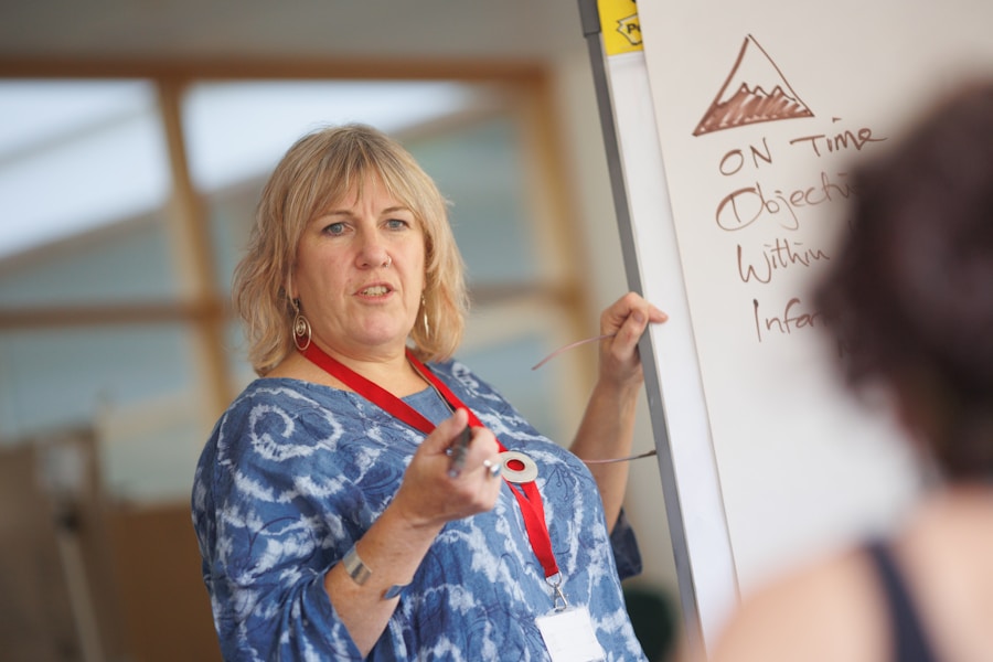 A woman is standing in front of a whiteboard with writing on it.