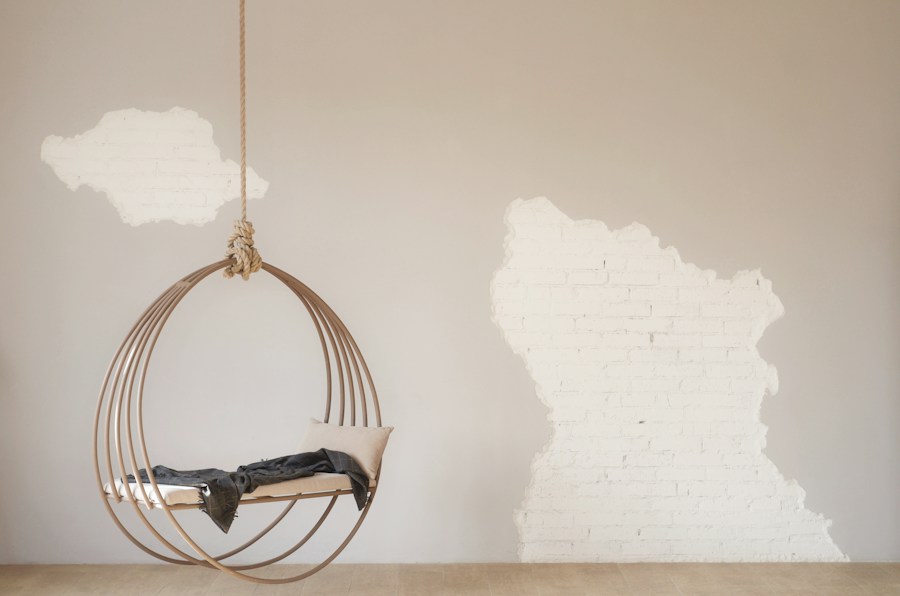 A hanging chair in a room with a white wall.