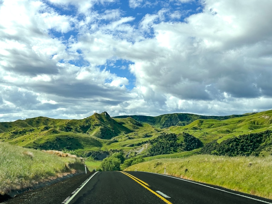 A road with green hills and blue sky.