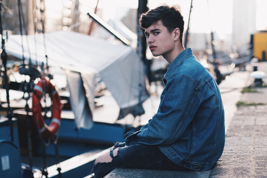 A young man sitting on the edge of a dock.