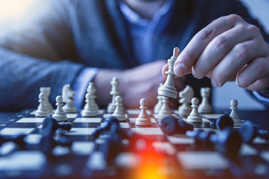 A man is playing chess on a chess board.