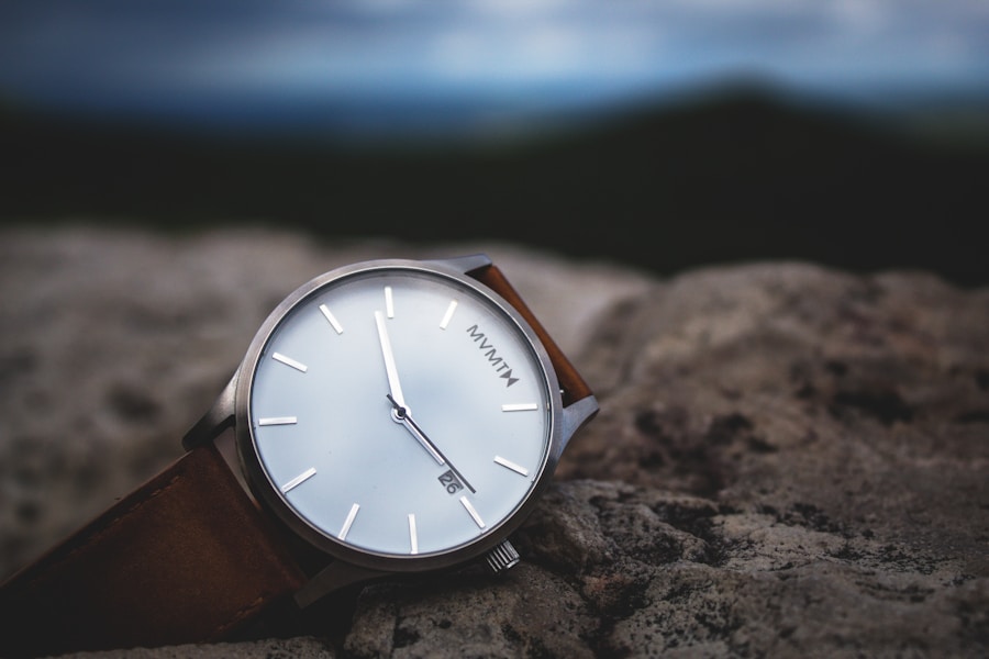 A watch sitting on a rock with mountains in the background.