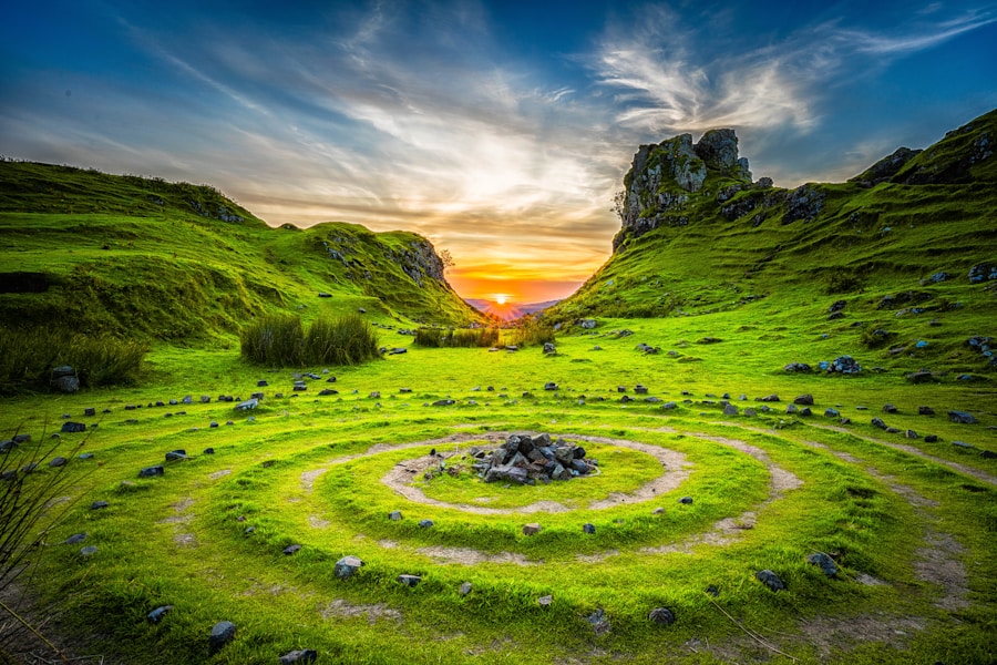 A circular stone circle in the middle of a grassy field at sunset.