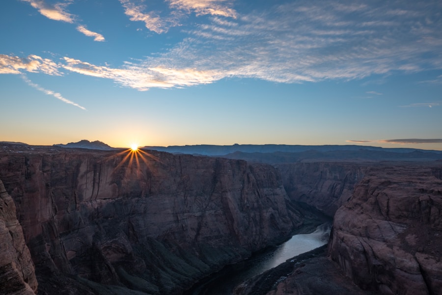 The sun rises over a canyon with a river in the background.