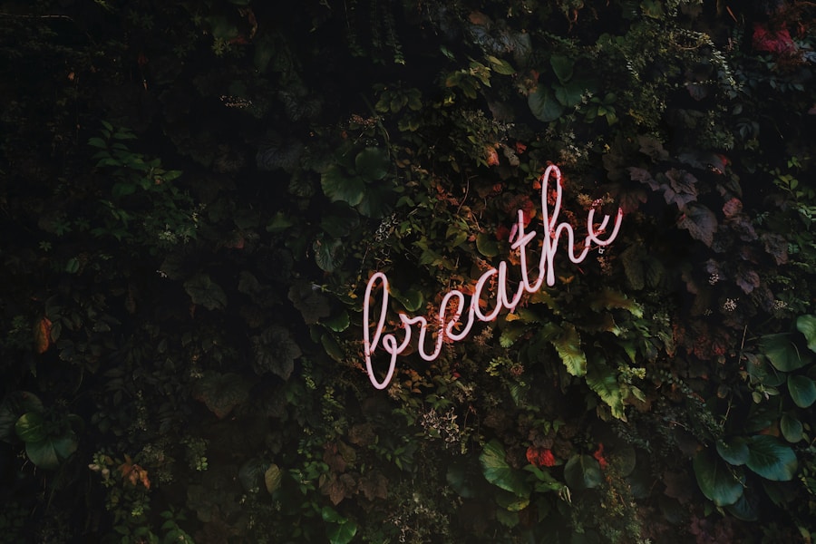 Neon sign reading "breathe" against a lush, green plant wall.