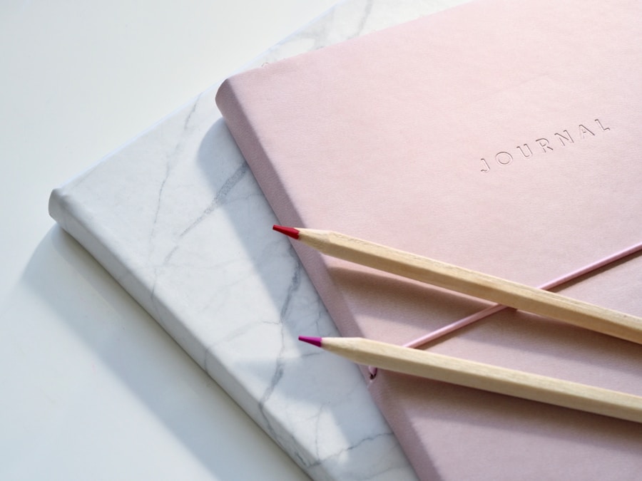 Pink journal and pencils on a marble-patterned surface.