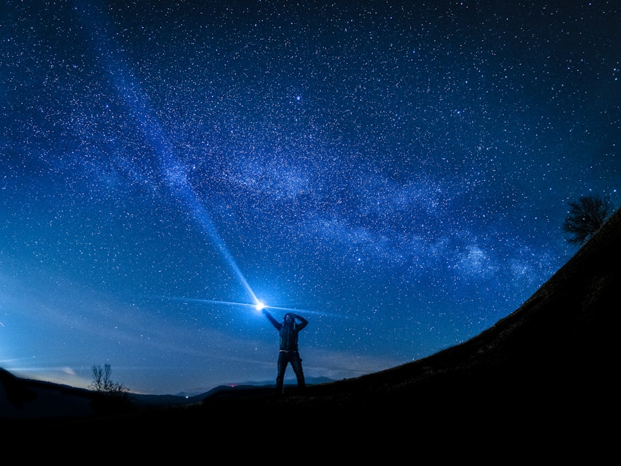 Person standing under a starry night sky, shining a flashlight towards the heavens.