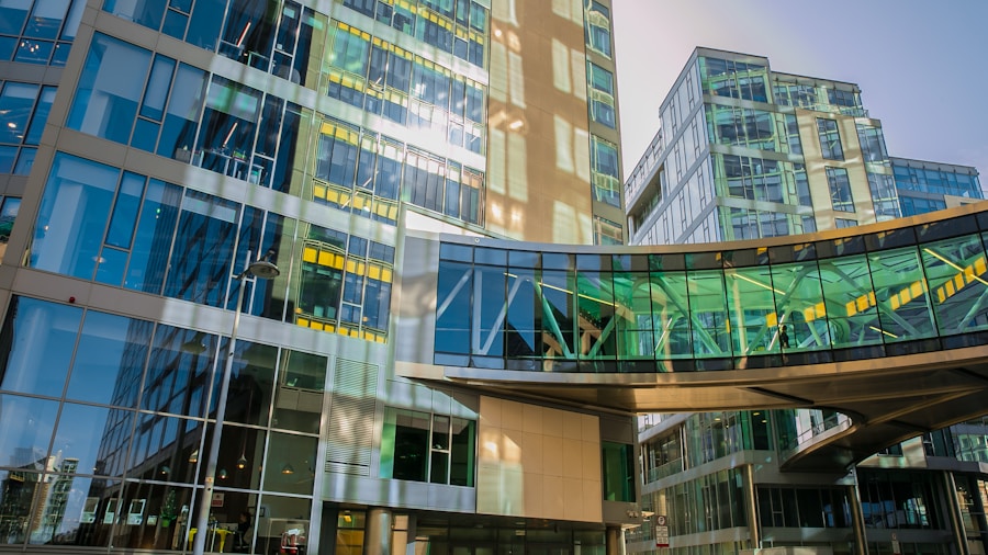 Modern glass buildings with a connecting skywalk against a clear blue sky.