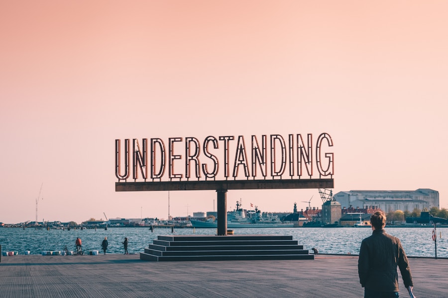 A person walking towards a large outdoor sign that reads "understanding" at sunset.