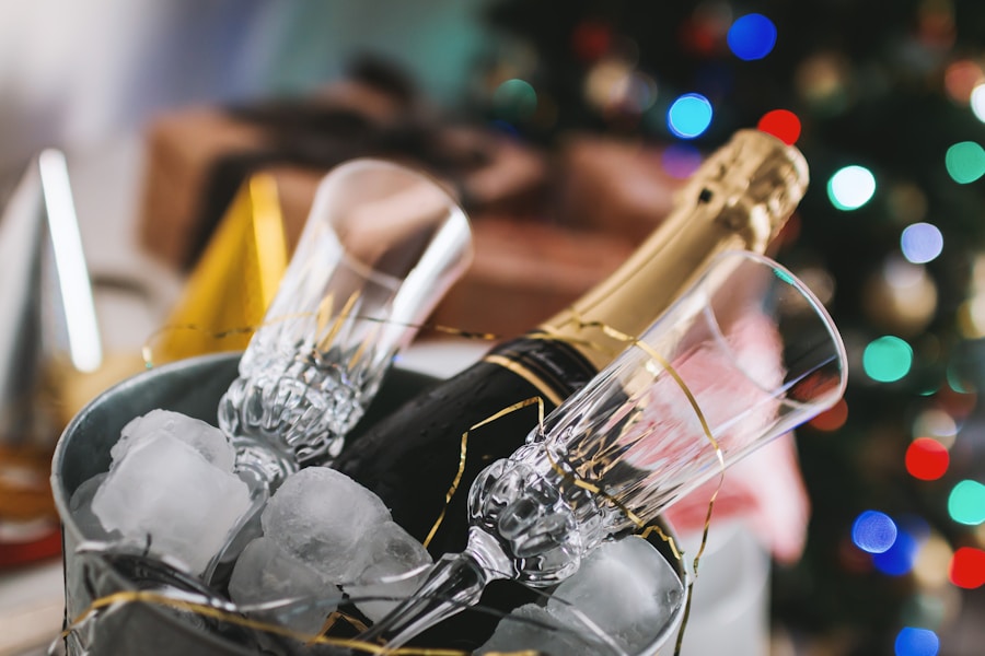 A bottle of champagne in a bucket with ice and two champagne glasses, with blurry christmas lights in the background.