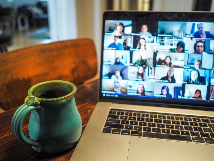 A laptop displaying a virtual group meeting next to a ceramic mug on a wooden table.