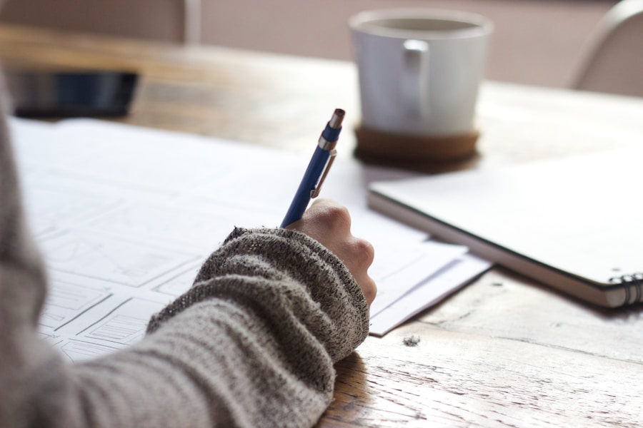 Person writing on a sheet of paper at a wooden table with a coffee cup in the background depicting choosing the ideal niche for your authority blog