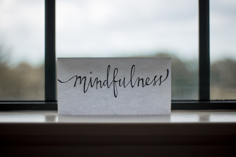 A card with the word "mindfulness" written in cursive, placed on a windowsill with a blurred natural background.