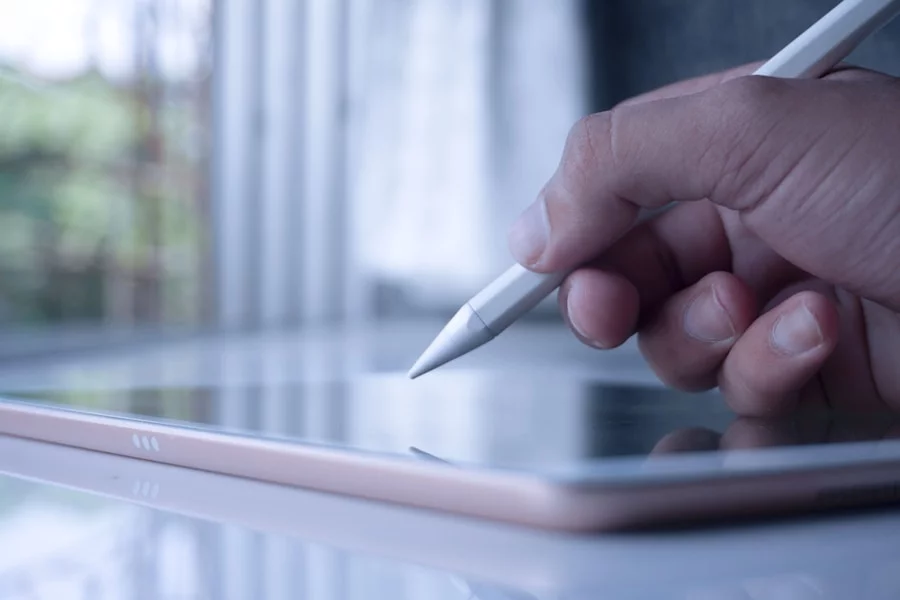 Close-up of a hand holding a stylus above a digital tablet depicting virtual assistant jobs