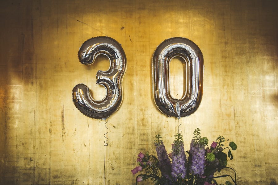 Silver number balloons forming the number 30 with a bouquet of flowers below against a textured golden background.