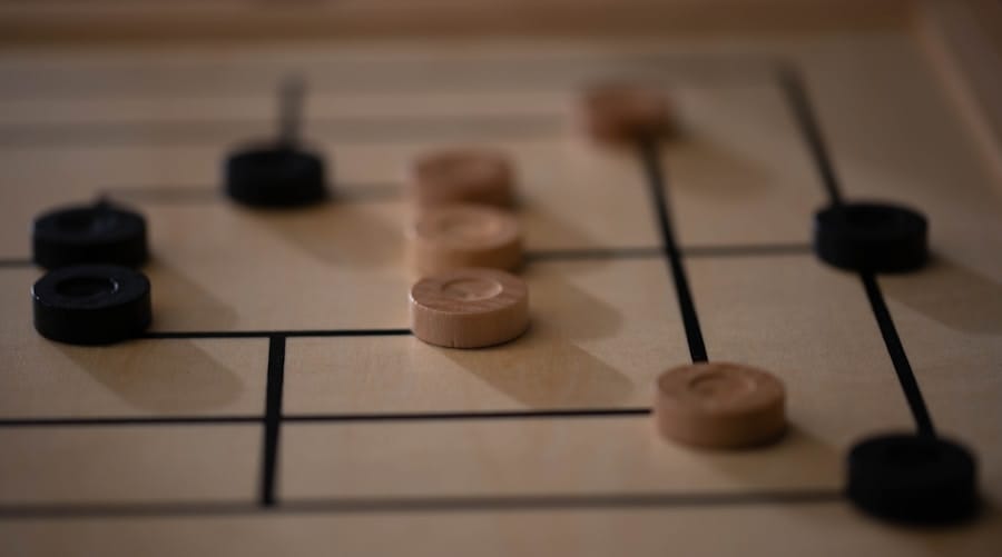 A wooden board game with dark and light round pieces placed on intersecting lines.